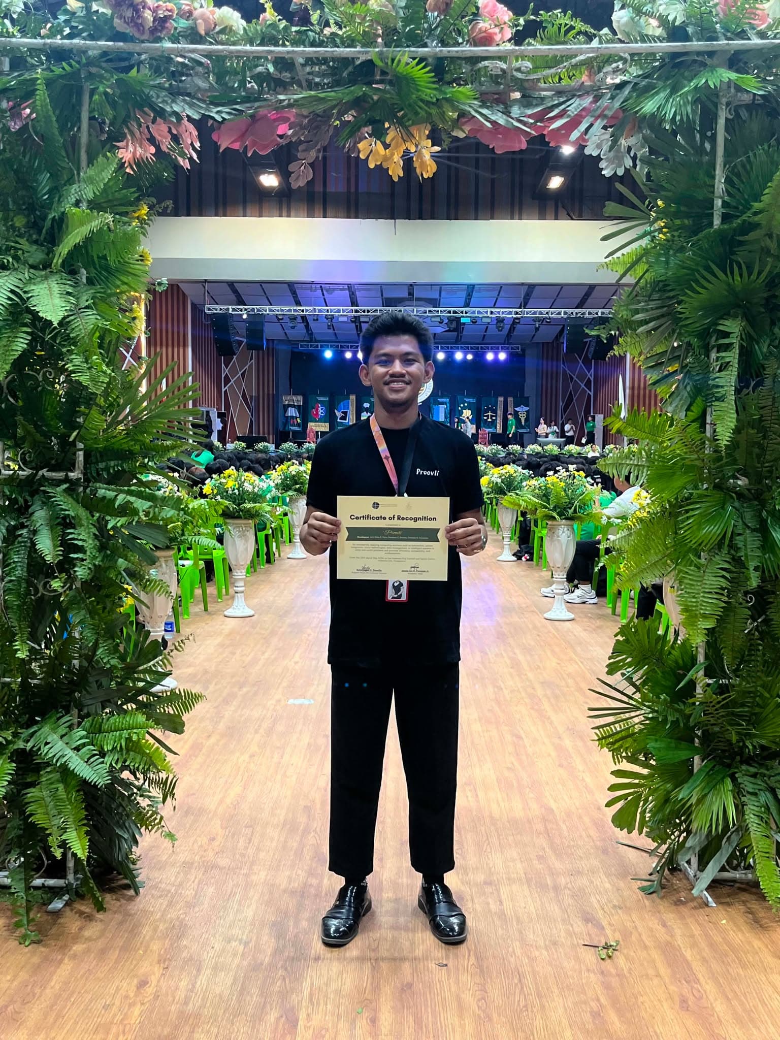 A Proovli team member holding the certificate of recognition at the venue stage entrance.